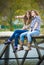 Two school girls sitting on river bridge