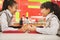 Two school girls talk over lunch in school cafeteria