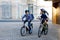 Two school kid boys in safety helmet riding with bike in the city with backpacks. Happy children in colorful clothes