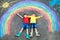 Two school kids boys having fun with with rainbow picture drawing with colorful chalks on asphalt. Siblings, twins and