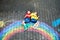 Two school kids boys having fun with with rainbow picture drawing with colorful chalks on asphalt. Siblings, twins and