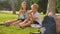 Two schoolchildren are eating sandwiches on the lawn of the school yard, school backpacks in the foreground.