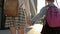 Two schoolgirls of different ages with backpacks return from school holding hands. The older sister helps the younger