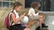 Two schoolgirls of different ages are sitting on a bench in the school yard. Little girl plays with a globe, the eldest