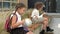 Two schoolgirls of different ages are sitting on a bench in the school yard. Little girl plays with a globe, the eldest