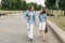 Two schoolgirls are holding a tablet in their hands and watching a video, laughing on the way to school. Friends