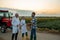 Two scientist speaking with young farmer in front of tractor and sunflower and soy field