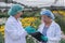 Two scientist women with lab gown and hair cover stand in front of multi-color flowers.smiling with the concept of good experiment