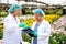 Two scientist women work together in experimental field of flower garden, one woman check the product and the other one record