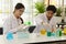 Two of scientist working in a laboratory examining test tubes with colorful liquids. and a female chemist is recording the day.