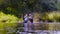 Two scientists ecologists in high rubber boots standing in the water of the forest river