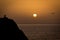 Two seagulls meeting in a rock in front of the sea while the sun is setting at the horizon