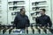 Two sell managers talking at the counter of the gun shop, rifles placed on stand
