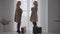 Two senior blonde Caucasian women in elegant beige coats walking with travel bags to the window. Rich senior