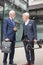 Two senior businessmen talking in front of an office building