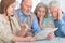 Two senior couples sitting at table and reading newspaper