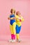Two senior elderly woman in colorful sportswear posing against pink studio background. Fitness. Concept of sport and