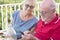 Two senior friends enjoy and look the phone cellular together with curiosity - outdoor mature people and connection technology