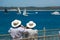 Two senior men watch sail boats with binoculars.