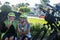 Two senior people cyclists with yellow helmet have a break in a green park eating a fruit and smiling. Moment of relaxation with