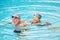 Two seniors or mature caucasia people together at the swimming pool - active woman and man doing exercise together at the pool to