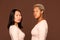 Two serious girls of African and Asian ethnicities in pullovers looking at you