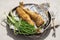 Two served grilled navaga fish on a tray with foil