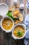 Two servings of chicken soup with croutons, vegetables, fresh parsley in a white bowl on a wooden table. Top view. Vertical shot