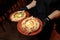 Two servings of khachapuri from tender tender dough with cheese and butter. The waiter`s hands in black gloves hold two