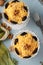 Two servings of salad with chicken, cheese and apples, decorated prunes and walnuts in glass bowls on light blue background