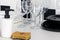 Two sets of white and black dishes next to the wine glasses behind the sponge and detergent