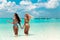 Two sexy bikini models having fun on tropical beach, exotic Maldives island. Summer vacation. Happy smiling women in fashion