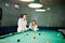 Two sexy girls in white bathrobe play pool billiards