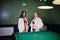 Two sexy girls in white bathrobe and swimsuit play pool billiards