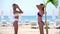 Two sexy young young girls taking shower on empty beach on tropical resort