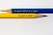 Two sharpened pencils in blue and yellow point in different directions isolated against a white background with the phrase: a goal