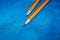 Two sharpened simple pencils lie on a blue background