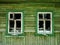 Two shattered Windows on an old green wooden house