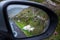 Two sheep lying on a grass close to a road . Reflection in a car mirror. Connemara, Ireland