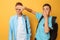 Two shocked teenagers close their eyes against a yellow background for fear