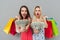 Two shocked women holding shopping bags and showing money