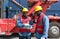 Two short black hair man with moustache and beard dressed in hardhat, safety vest and protective glove working during the day