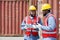 Two short black hair man with moustache and beard dressed in yellow hardhat, red safety vest and white protective glove working