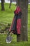 Two shovels and red work jacket near tree on green grass background, concept of spring garden or park work, selective focus