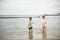 Two sibling little brother boy exploring the beach at low tide w