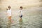 Two sibling little brother boy exploring the beach at low tide walking towards the sea coast. Friendship happy childhood concept