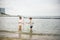 Two sibling little brother boy exploring the beach at low tide walking towards the sea coast. Friendship happy childhood concept