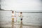 Two sibling little brother boy exploring the beach at low tide walking towards the sea coast. Friendship happy childhood concept