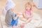 Two siblings - boy and girl - in chef`s hats sitting on the kitchen floor soiled with flour, playing with food, making mess and ha