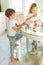 Two siblings brother and sister toddler boy tween girl painting easter eggs on kitchen at home on the spring sunny day
